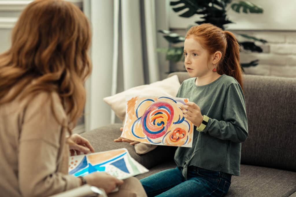 A young girl and a woman having a conversation about the photo on the girls hand.